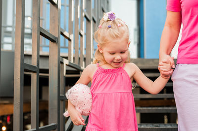 Portrait of smiling young woman standing by railing