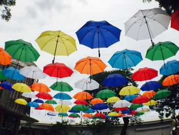 Low angle view of multi colored umbrellas hanging against sky