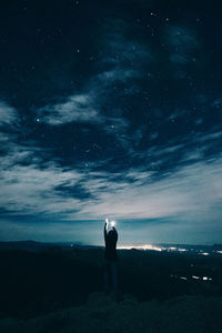 Rear view of silhouette person standing against sky at night