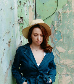 Portrait of young woman standing against wall