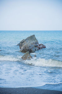 Scenic view of rocks in sea against clear sky
