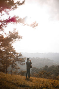 Man photographing while standing on land against sky