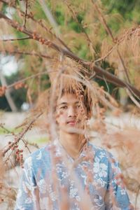 Portrait of man standing below branch