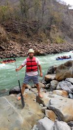 Full length of man standing on rock by river