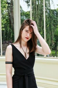 Beautiful young woman standing against trees