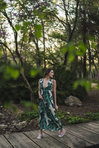Full length of woman standing on footpath amidst trees in forest
