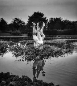 White men standing on tree by lake against sky