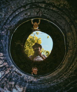 Reflection of man photographing frogs in water