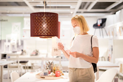 Side view of woman wearing mask standing at store