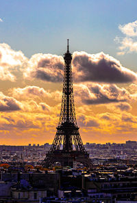 Communications tower in city against sky during sunset