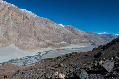 Scenic view of lake and mountains against clear blue sky