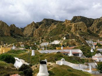 Houses on mountain against cloudy sky