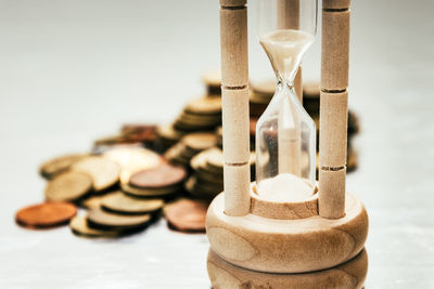 Close-up of hourglass and coins on table