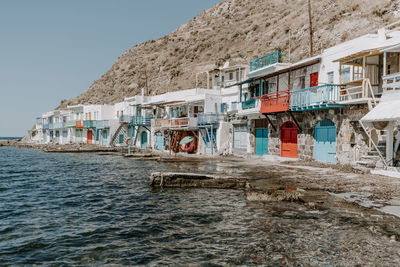 Buildings by sea against clear sky