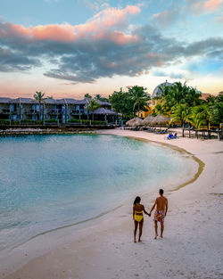 People on beach against sky during sunset