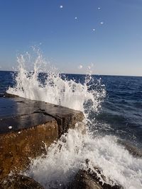 Waves splashing on shore against sky