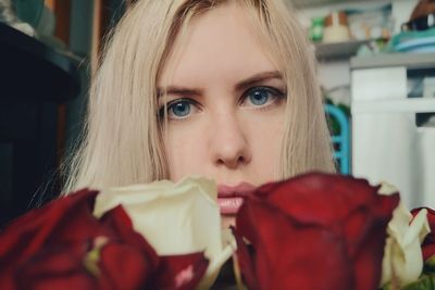 Close-up portrait of young woman by roses