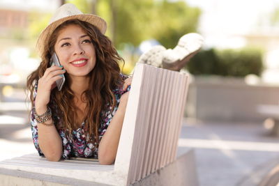 Portrait of young woman using phone while sitting on table