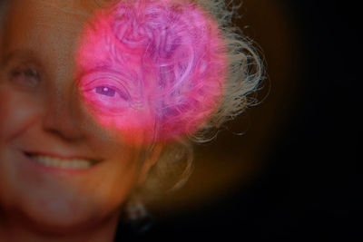 Close-up portrait of smiling young woman against black background