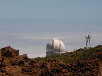 Scenic view of rocks  and astronomy telescope against sky