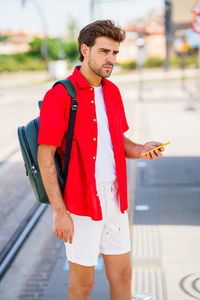 Young man looking away while standing outdoors