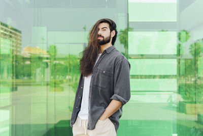 Young man standing against window