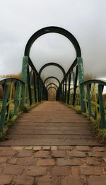 Footbridge over footpath against sky