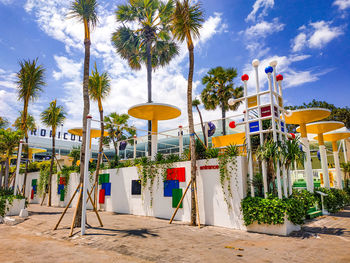 Low angle view of palm trees by building against sky