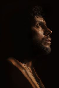 Close-up of man looking away against black background