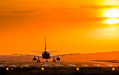 Airplane on airport runway during sunset