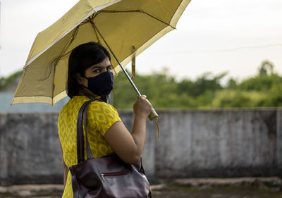 An indian woman in yellow dress and face mask on is going outside after unlock 1.0 of corona virus