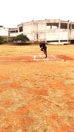 Man running on field against built structure