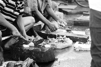 Low section of men cutting fish