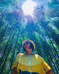 Low angle portrait of young woman against sky on sunny day