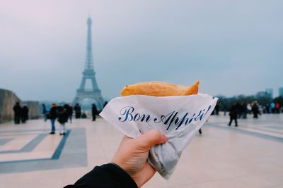 Close-up of hand holding crepe against eiffel tower