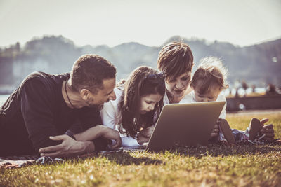 Parents with daughters using laptop on land