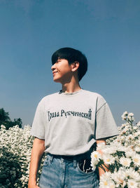 Full length of a boy standing on rock against sky