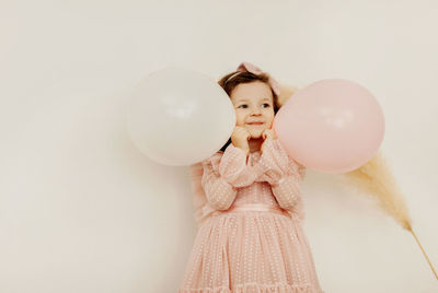A charming little girl with balloons on her birthday has fun and laughs