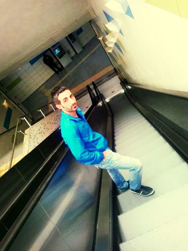 indoors, casual clothing, lifestyles, person, full length, architecture, leisure activity, young adult, built structure, standing, sitting, steps, front view, blue, young men, high angle view, looking at camera, three quarter length