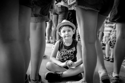 Portrait of boy sitting on street amidst crowd