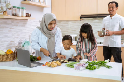 Full length of mother and daughter in kitchen