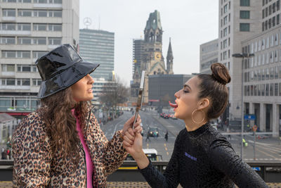 Friends with mirror standing in city