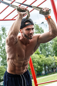 Shirtless muscular man exercising in park