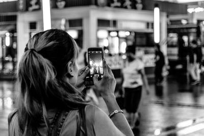 Rear view of woman photographing against building