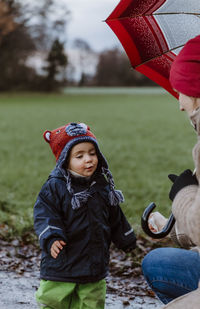 Mother and cute daughter wearing warm clothing on field