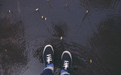 Low section of person standing on puddle during monsoon