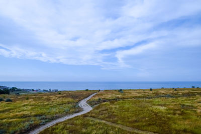 Scenic view of road by sea against sky