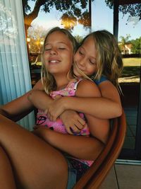 Smiling girl with sister sitting on chair