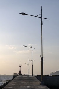 Low angle view of street light on sea wall against sky