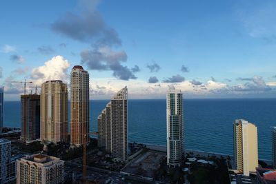 Modern buildings by sea against sky in city